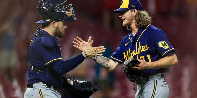 Milwaukee Brewers' Victor Caratini, 左, high-fives Josh Hader after the final out a baseball game against the Cincinnati Reds in Cincinnati, 火曜日, 五月 10, 2022. The Brewers won 5-4.