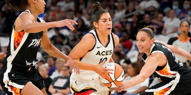 Kelsey Plum dribbling past defenders on the court.