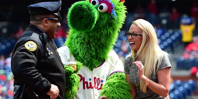 Fox Sports field reporter Kelsey Wingert and the Phille Phanatic share a laugh with a Philadelphia Police officer during a Major League Baseball game between the Atlanta Braves and the Philadelphia Phillies on April 23, 2017 at Citizens Bank Park in Philadelphia, PA . Phillies won 5-2.