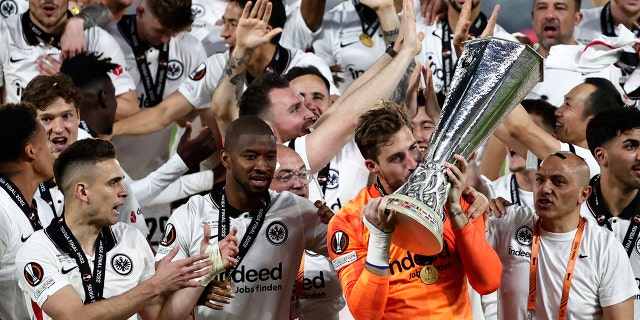 قبل حارس فرانكفورت كيفين تراب الكأس للفائزين بنهائي الدوري الأوروبي لكرة القدم بين أينتراخت فرانكفورت ورينجرز في ملعب رامون سانشيز بيزخوان في إشبيلية ، إسبانيا ، يوم الخميس 19 مايو 2022.
