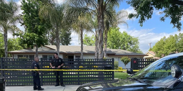 Los Angeles police officers stand outside a home where three children were found dead Sunday. A Los Angeles woman allegedly killed her three children on Mother's Day and a teenager has also been arrested in connection with the slayings, police said.