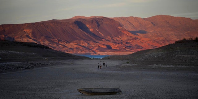 A formally sunken boat sits on cracked earth hundreds of feet from what is now the shoreline on Lake Mead at the Lake Mead National Recreation Area, Monday, May 9, 2022, near Boulder City, Nev.