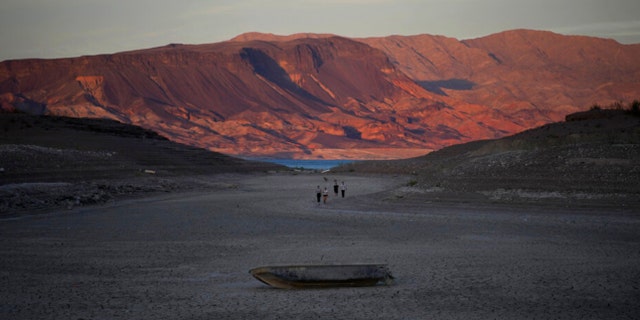 A formally sunken boat sits on cracked earth hundreds of feet from what is now the shoreline on Lake Mead at the Lake Mead National Recreation Area, Monday, May 9, 2022, near Boulder City, Nev.