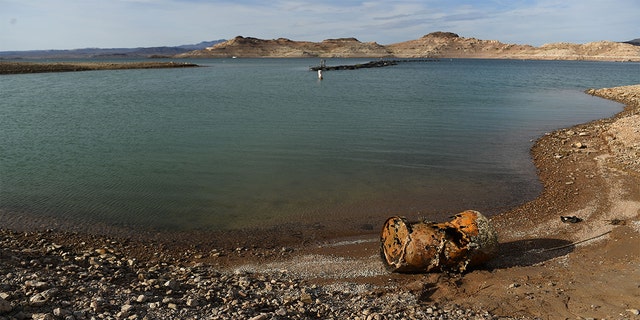 A rusted metal barrel, near the location of where a different barrel was found containing a human body, sits exposed on shore during low water levels due to the western drought at the Lake Mead Marina on the Colorado River in Boulder City, Nevada on May 5, 2022. 