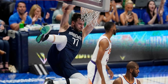 Dallas Mavericks guard Luka Doncic (77) hangs on the rim over Phoenix Suns guard Chris Paul, derecho, after scoring during the second half of Game 6 of an NBA basketball second-round playoff series, jueves, Mayo 12, 2022, en dallas.