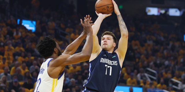 Le gardien des Dallas Mavericks Luka Doncic (77 ans) tire contre l'attaquant des Golden State Warriors Andrew Wiggins lors de la première moitié du deuxième match des finales de la Conférence Ouest des éliminatoires de basket-ball de la NBA à San Francisco, le vendredi 20 mai 2022.