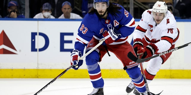 New York Rangers center Mika Zibanejad (93) passes in front of Carolina Hurricanes defenseman Brady Skjei in the first period of Game 3 of an NHL hockey Stanley Cup second-round playoff series, Sunday, May 22, 2022, in New York.