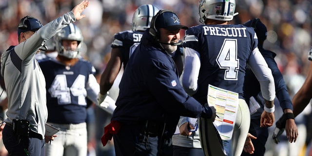 Head coach Mike McCarthy of the Dallas Cowboys celebrates with Dak Prescott after successfully converting a two-point conversion against the Washington Football Team at FedExField on Dec. 12, 2021, in Landover, Maryland.