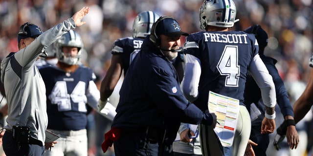 Head coach Mike McCarthy of the Dallas Cowboys celebrates with Dak Prescott after successfully converting a two-point conversion against the Washington Football Team at FedExField on Dec. 12, 2021, in Landover, Maryland.