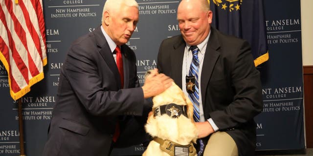Former Vice President Mike Pence pets a police dog that was born in Pence's home state of Indiana during a roundtable discussion the former vice president had with law enforcement members May 26, 2022, at the New Hampshire Institute of Politics in Goffstown, N.H.