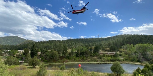 A Chinook Helicopter dips out of Monastery Lake in the West Zone of New Mexico's Hermits Peak and the Calf Canyon Fires.