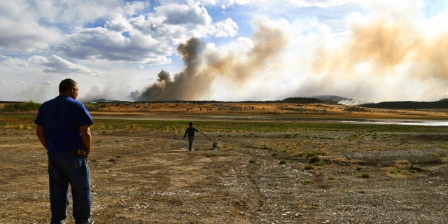 Leonard Padilla and 5-year-old Ivan Padilla watch a wildfire burning near Las Vegas, N.M., on Tuesday, May 3, 2022. 