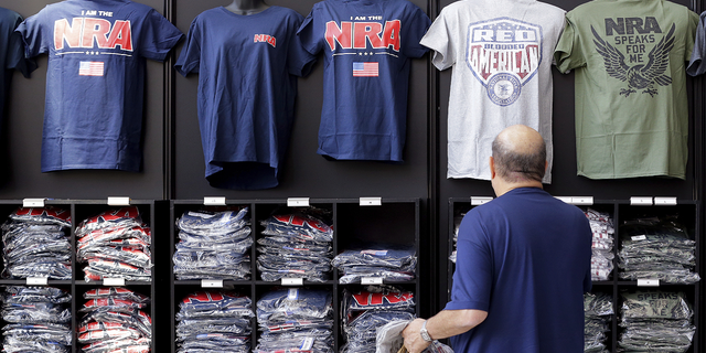 A convention attendee looks at NRA branded shirts for sale at the NRA Store at the NRA Annual Meeting in Houston, 德州, 星期四, 可能 26.