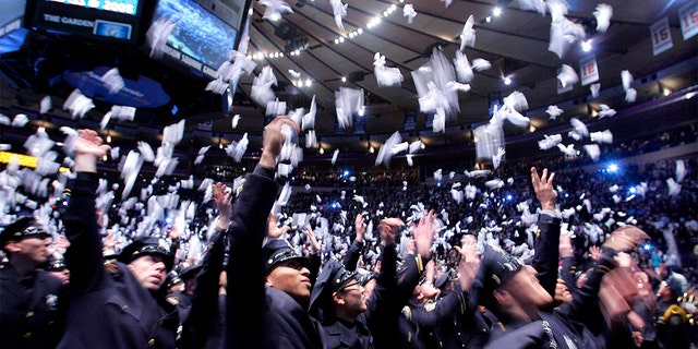 A New York Police Department class tosses white gloves into the air to celebrate graduation from the NYPD Police Academy.