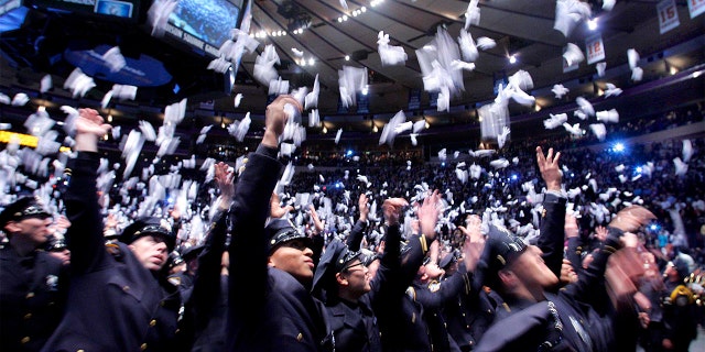 A New York Police Department class tosses white gloves into the air to celebrate graduation from the NYPD Police Academy.