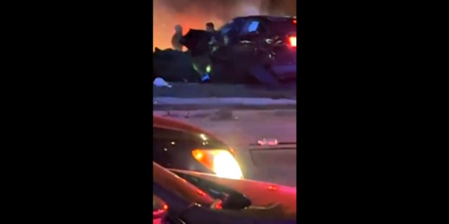 A damaged, black vehicle emits what appears to be smoke following a car crash in Lincoln, Nebraska, on Sunday.