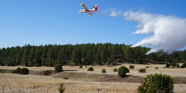 A scooper plane drops water to reinforce firing operations along New Mexico's Highway 283