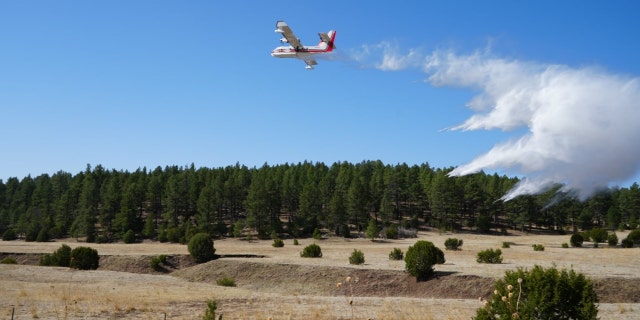A scooper plane drops water to reinforce firing operations along New Mexico's Highway 283