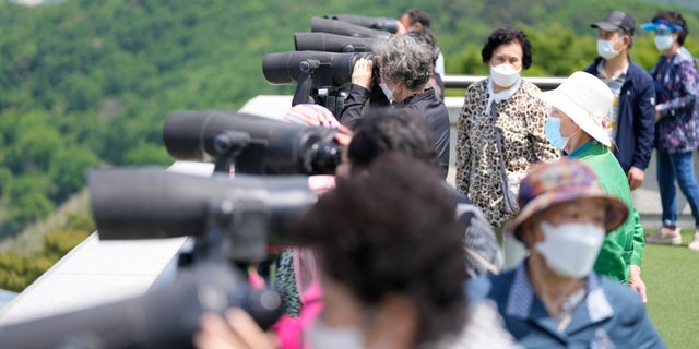 بازدیدکنندگان از دوربین دوچشمی برای دیدن سمت کره شمالی از رصدخانه اتحاد در پاجو، کره جنوبی، پنجشنبه، 12 می 2022 استفاده می کنند. (AP Photo/Lee ​​Jin-man)