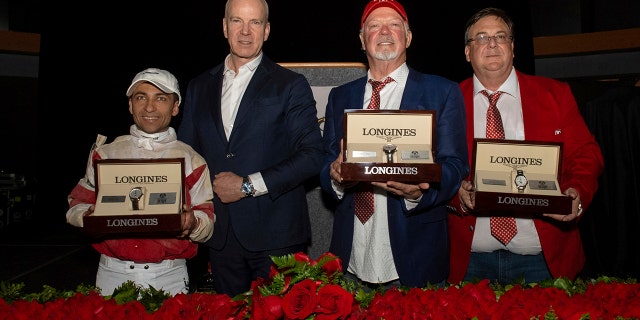 Matthias Breschan, second from left, Longines CEO, presents timepieces to owner Richard Dawson, second from right, trainer Eric Reed, right, and jockey Sonny Leon after Rich Strike won the Kentucky Derby, Saturday, May 7, 2022, at Churchill Downs. Longines is the official watch and timekeeper of the 148th Derby.