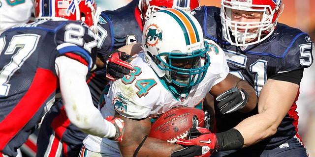 Ricky Williams (34) of the Miami Dolphins is tackled by Paul Posluszny (51) and Reggie Corner (27) of the Buffalo Bills Dec. 19, 2010, at Sun Life Stadium in Miami. 