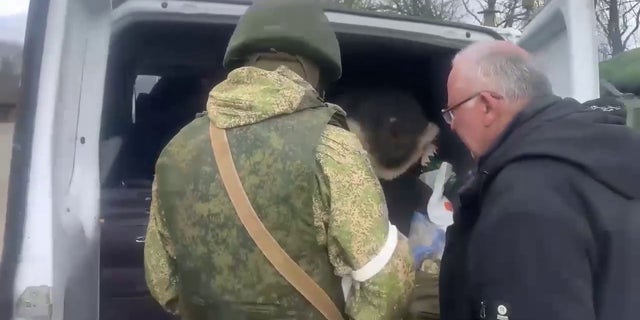 Russian forces search a vehicle at a checkpoint near Kharkiv, Ukraine.