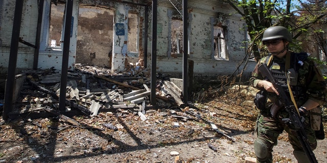 A police officer checks an area during an evacuation of local residents between shelling, amid Russia's attack on Ukraine, in the village of Novomykhailivka, in Donetsk region, Ukraine, May 29, 2022.