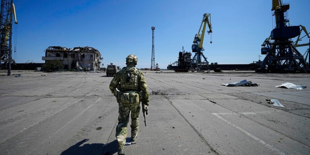 A Russian serviceman walks while guarding an area of the Mariupol Sea Port in Mariupol, in territory under the government of the Donetsk People's Republic, eastern Ukraine.