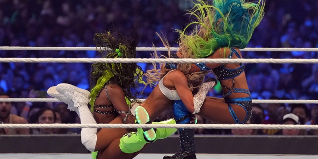 Apr 3, 2022; Arlington, TX, USA; Naomi (left) and Sasha Banks (right) attack Carmella during the women’s Tag Team Championship fatal four way match during WrestleMania at AT&amp;T Stadium.