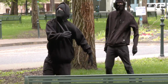 Black-clad demonstrators hurl projectiles toward GOP rallygoers supporting gubernatorial candidate Stan Pulliam in Portland, Oregon, on April 30, 2022.