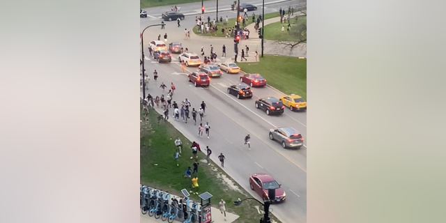A large group of young people run through the streets of Chicago on Wednesday, May 11, 2022.