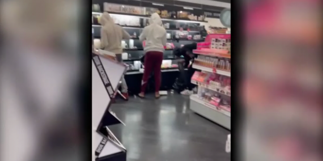 Thieves steal items off a shelves at Sephora beauty store in Los Angeles.
