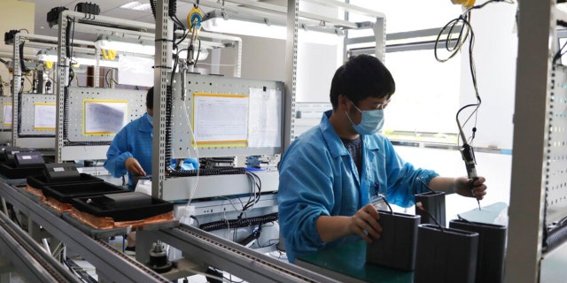 In this photo released by Xinhua News Agency, a staff members wearing masks work at a workshop in an industry park in Qingpu District of Shanghai, east China, May 17, 2022.