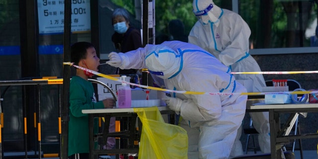 A child gets swabbed during mass COVID test on Friday, May 13, 2022, in Beijing.