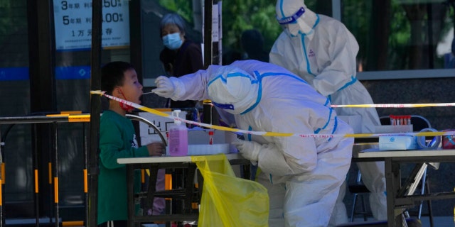 A child gets swabbed during mass COVID test on Friday, May 13, 2022, in Beijing.