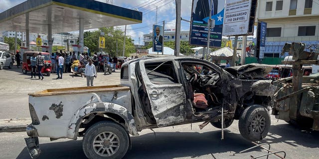 A destroyed vehicle is removed after a suicide bomb attack at a checkpoint near the airport in Mogadishu, Somalia, May 11, 2022. 