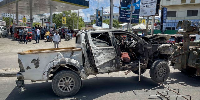 A destroyed vehicle is removed after a suicide bomb attack at a checkpoint near the airport in Mogadishu, Somalia, May 11, 2022. 