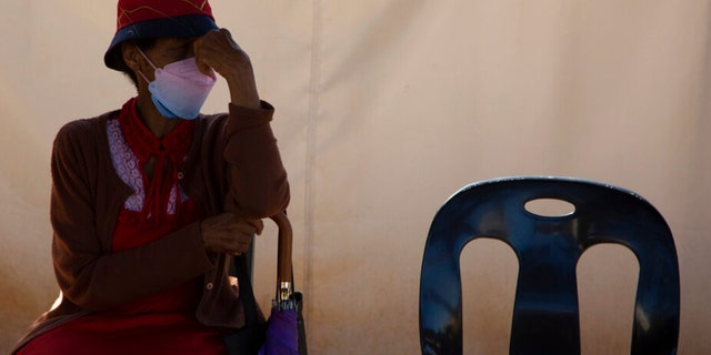 A woman waits in a queue to be screened for COVID-19 at a testing center in Soweto, South Africa, Wednesday, May 11, 2022. South Africa is experiencing a surge of new COVID-19 cases driven by two omicron sub-variants, According to health experts. 