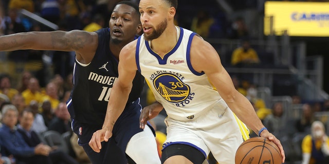 Le garde des Golden State Warriors Stephen Curry (30 ans) se dirige vers le panier contre l'attaquant des Dallas Mavericks Dorian Finney-Smith lors de la seconde moitié du match 2 des finales de la Conférence Ouest des éliminatoires de basket-ball de la NBA à San Francisco, le vendredi 20 mai 2022.