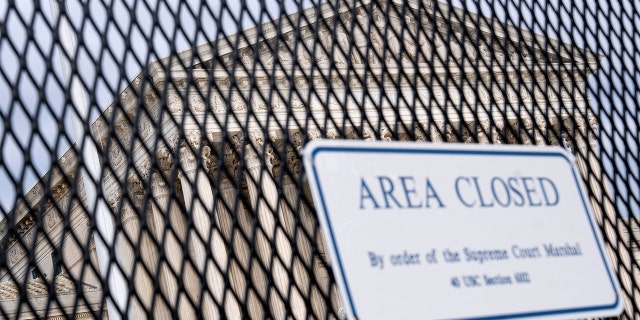 The U.S. Supreme Court is seen through a fence with a "Closed Area" sign in Washington, May 11, 2022.