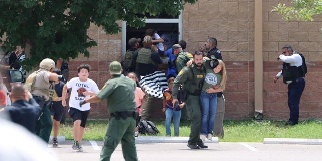 Children run to safety after escaping through a window during a mass shooting at Robb Elementary School where a gunman killed 19 children and two adults in Uvalde, Texas, U.S. May 24, 2022. 