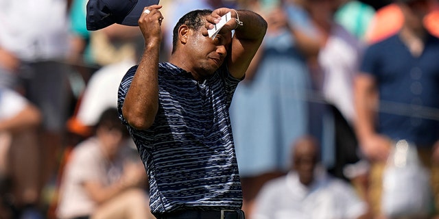 Tiger Woods wipes his face on the 18th hole during the first round of the PGA Championship golf tournament, Thursday, May 19, 2022, in Tulsa, Oklahoma.