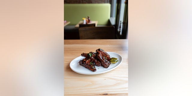 この "trashed ribs" recipe from St. Louis restaurant Salt + Smoke, are served with a side of crunchy bread and butter pickles.