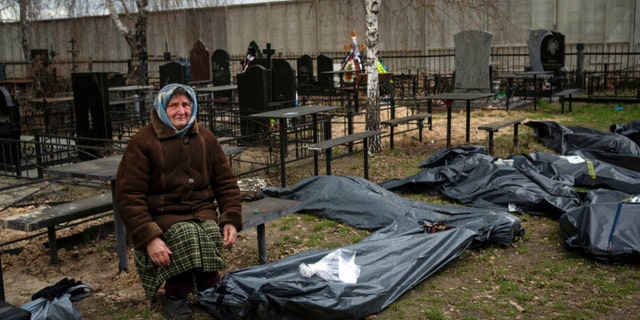 Nadiya Trubchaninova, 70, sits next to a plastic bag that contains the body of her son Vadym Trubchaninov, 48, who was killed by Russian soldiers in Bucha on March 30, in the outskirts of Kyiv, Ukraine, Tuesday, April 12, 2022. 