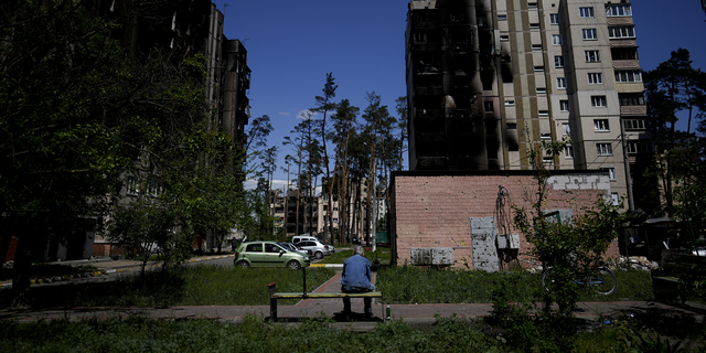A resident sits outside buildings damaged by shelling in Irpin, on the outskirts of Kyiv, Ukraine, on Tuesday, May 24.