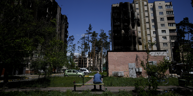 A resident sits outside buildings damaged by shelling in Irpin, on the outskirts of Kyiv, Ukraine, on Tuesday, May 24.