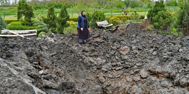 Orthodox Sister Evdokia gestures in front of the crater of an explosion, after Russian shelling next to the Orthodox Skete in honour of St. John of Shanghai in Adamivka, near Slovyansk, Donetsk region, Ukraine, Tuesday, May 10, 2022. 