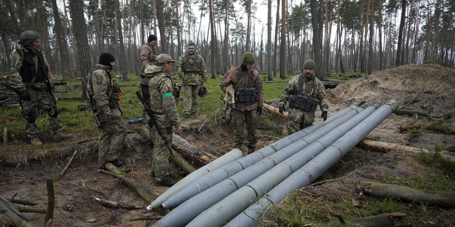 Украински войници проверяват множество руски ракети, оставени от руски сили, в село Березовка, Украйна, на 21 април.