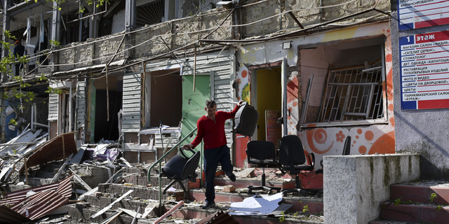 رجل يحمل الكراسي خارج مكتب في الطابق الأرضي من مبنى سكني دمره قصف ليلي في كراماتورسك ، أوكرانيا ، يوم الخميس ، 5 مايو.