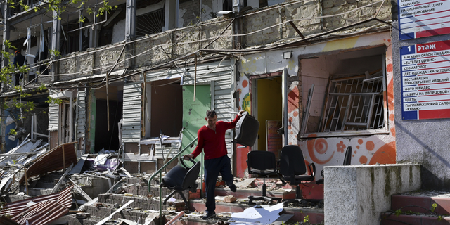 A man carries chairs out of an office on a ground floor of an apartment building destroyed by night shelling in Kramatorsk, Ukraine, on Thursday, May 5.